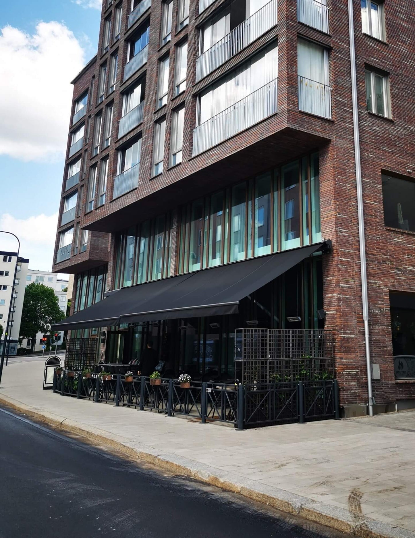 Jamaica inkl skyddshuv i Antracit - FSM71319 samt svart markisväv monterad över restaurangens uteservering. Elektrisk styrning inklusive skaksensor som tillval för att markisen skall stängas när vinden börjar blåsa.