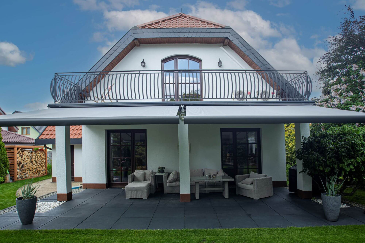 Robust, kvalitativ, grå terrassmarkis, markisen har grå silver RAL9006 konstruktion med ljusgrå markisväv. Monterad på en uteplats med stenplattor och gräsmatta. Premium Markis, modell Palladio. premium-markis.se