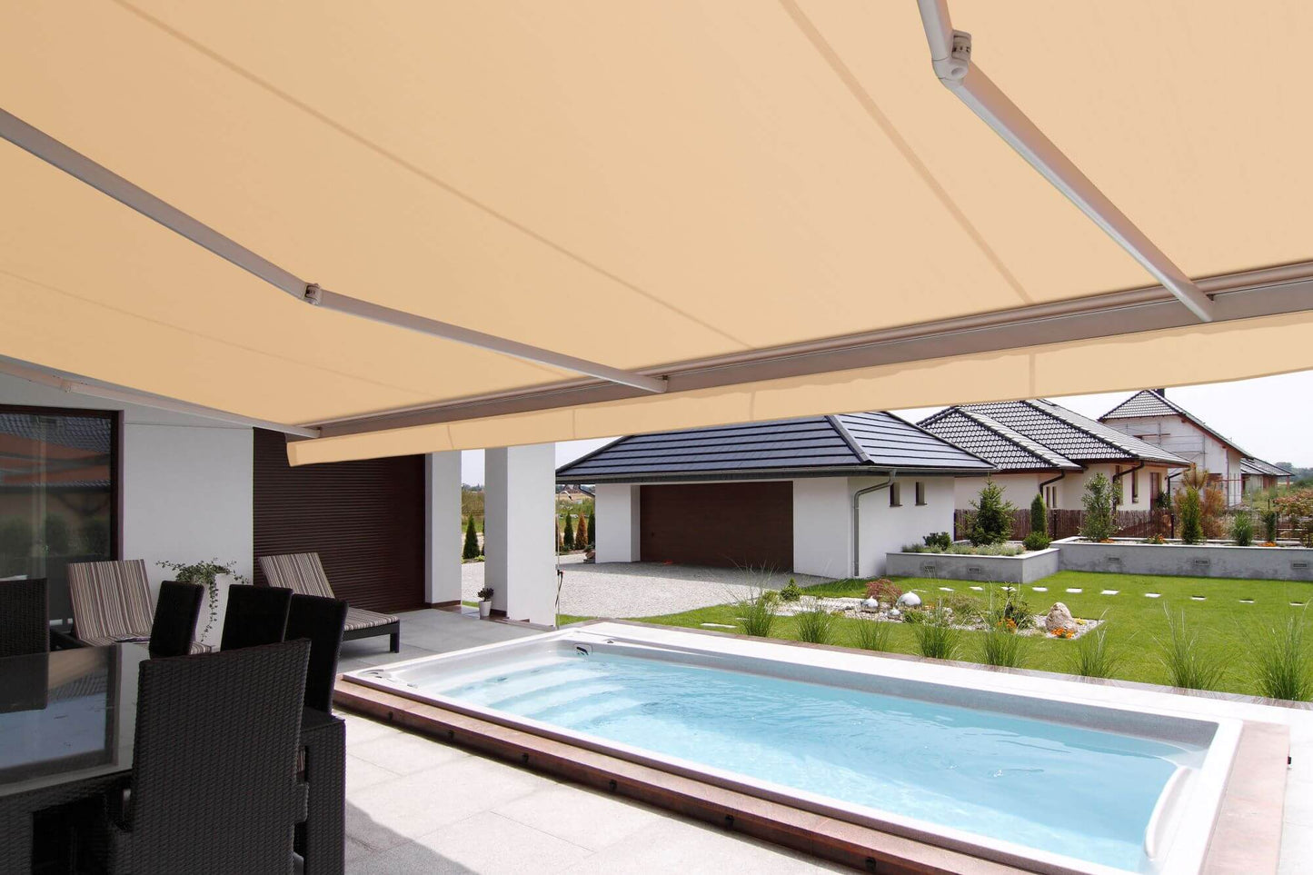 Robust, kvalitativ, grå terrassmarkis med volang, markisen har grå konstruktion med beige markisväv. Monterad på en uteplats med pool. Premium Markis, modell Palladio. premium-markis.se
