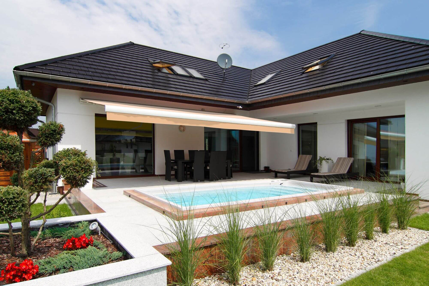 Robust, kvalitativ, grå terrassmarkis med volang, markisen har grå konstruktion med beige markisväv. Monterad på en uteplats med pool. Premium Markis, modell Palladio. premium-markis.se