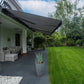 Robust, kvalitativ, grå terrassmarkis, markisen har grå silver RAL9006 konstruktion med ljusgrå markisväv. Monterad på en uteplats med stenplattor och gräsmatta. Premium Markis, modell Palladio. premium-markis.se